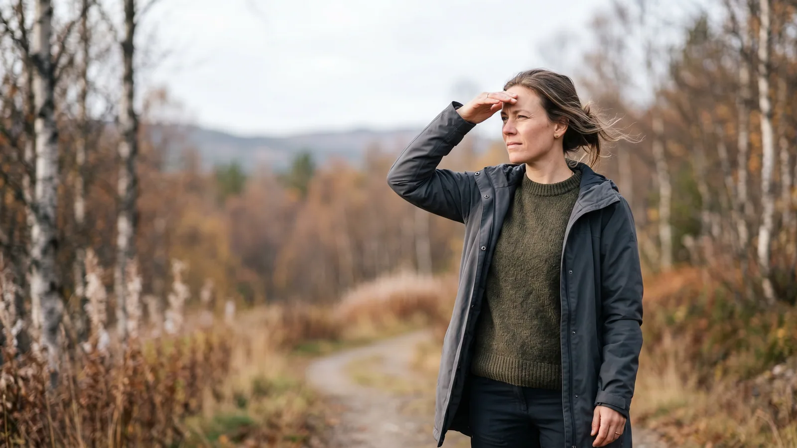 En person kniber øjnene sammen mod skarpt lys ved et vindue, mens den anden hånd skygger for ansigtet