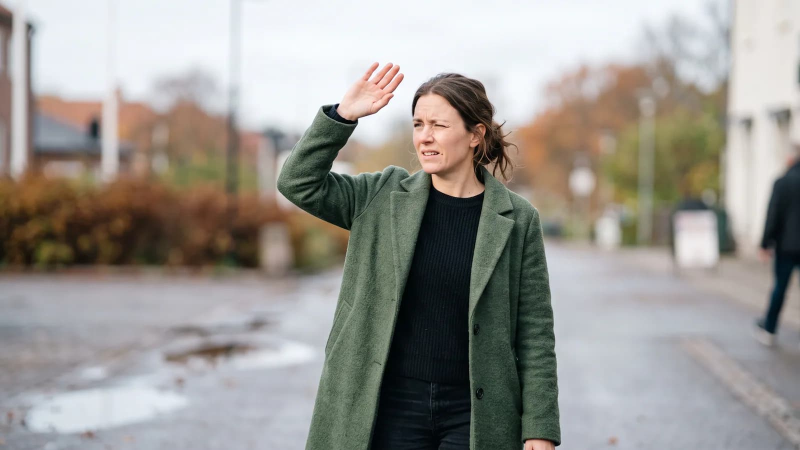 En person kniber øjnene sammen mod skarpt lys ved et vindue, mens den anden hånd skygger for ansigtet